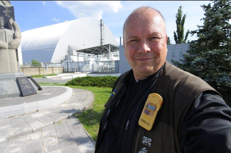 Christian med kärnkraftverket i bakgrunden. Notera geigermätaren på hans bröst. Det gällde att ständigt ha koll, så att gränsvärdena inte överskreds